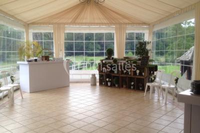Salle décorée avec des ballons blancs et dorés, rangées de chaises rouges alignées sur un tapis rouge.