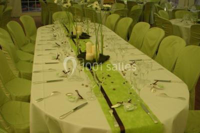 Salle décorée avec des ballons blancs et dorés, rangées de chaises rouges alignées sur un tapis rouge.