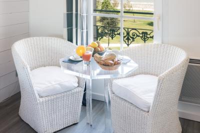 Salle de réunion avec des chaises dorées à assise rouge, une table ronde au premier plan et des tableaux accrochés au mur.
