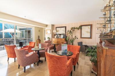 Salle de réunion avec des chaises dorées à assise rouge, une table ronde au premier plan et des tableaux accrochés au mur.