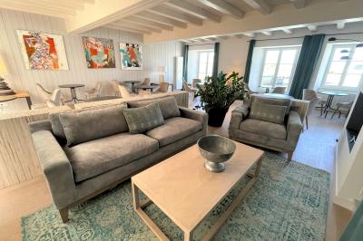 Salle de réunion avec des chaises dorées à assise rouge, une table ronde au premier plan et des tableaux accrochés au mur.