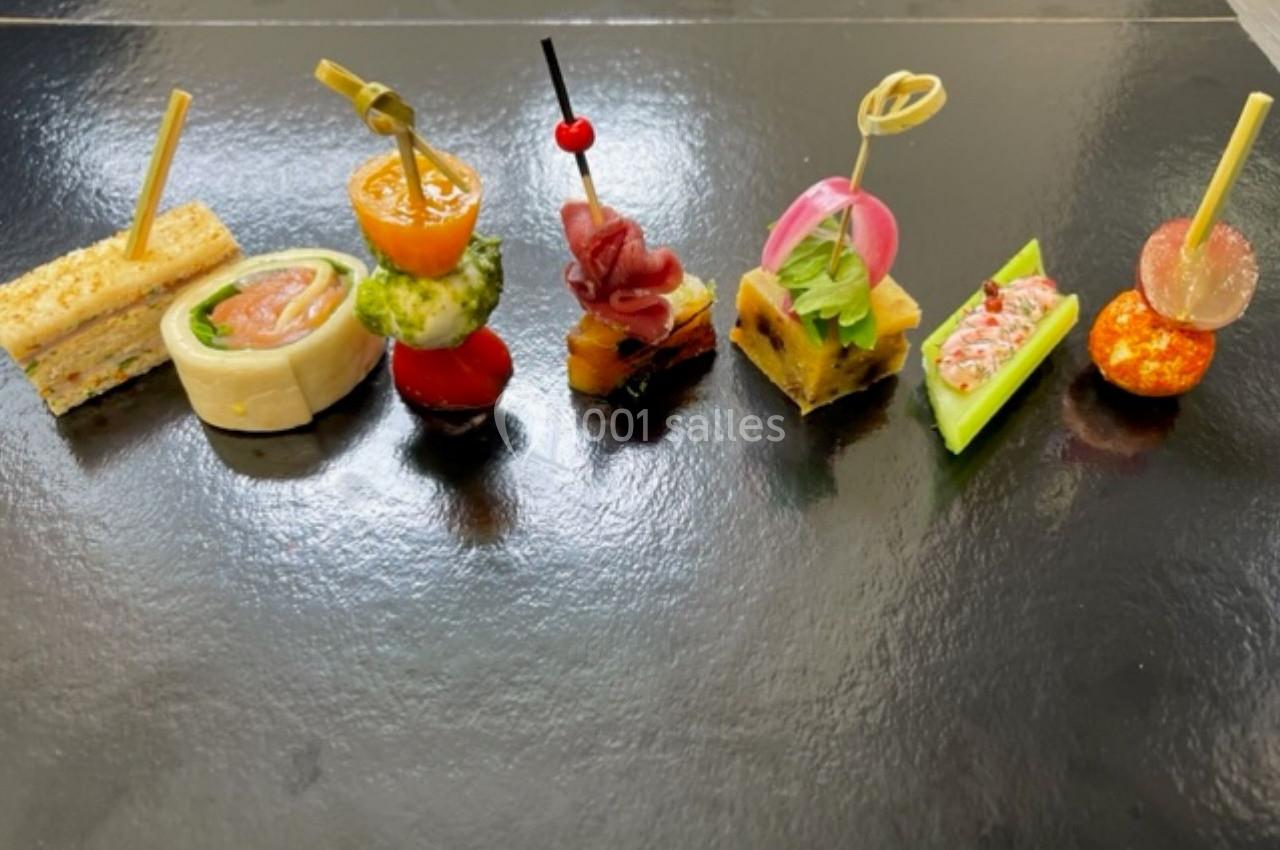 Assortiment de bouchées apéritives variées présentées sur une surface noire.