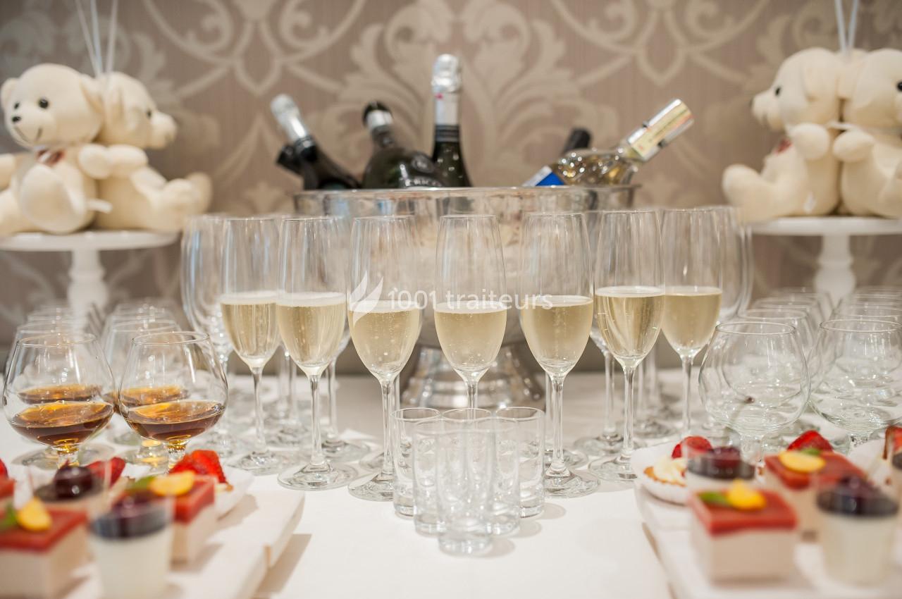 Table avec flûtes de champagne, verrines, desserts et seau à glace contenant des bouteilles, décorée de peluches.