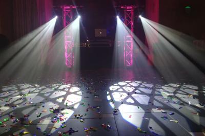 Jeu de lumières colorées projetées depuis une installation de DJ avec une table et des structures lumineuses.