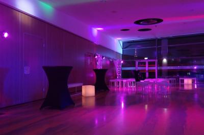 Jeu de lumières colorées projetées depuis une installation de DJ avec une table et des structures lumineuses.