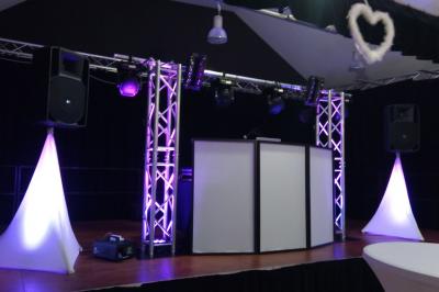 Jeu de lumières colorées projetées depuis une installation de DJ avec une table et des structures lumineuses.