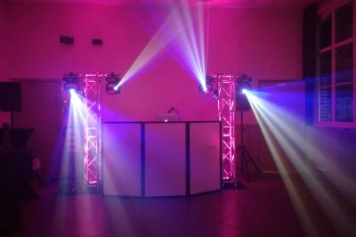 Jeu de lumières colorées projetées depuis une installation de DJ avec une table et des structures lumineuses.
