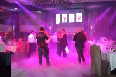 Deux hommes dansent ensemble sur une piste éclairée par des lumières colorées dans une ambiance festive.