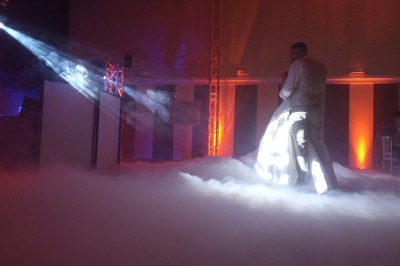 Deux hommes dansent ensemble sur une piste éclairée par des lumières colorées dans une ambiance festive.