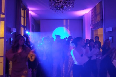 Deux hommes dansent ensemble sur une piste éclairée par des lumières colorées dans une ambiance festive.