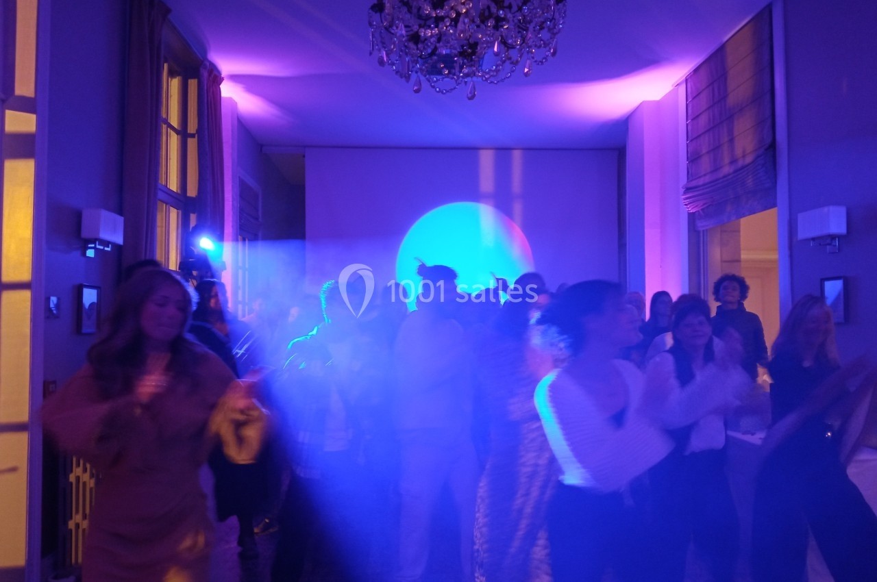 Groupe de personnes dansant dans une salle éclairée par des lumières colorées, ambiance festive.