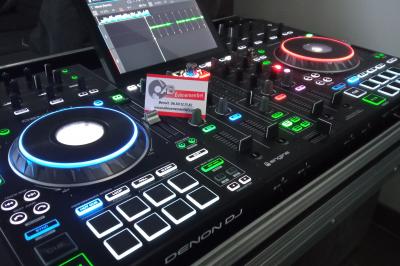 Mur en briques éclairé par des lumières rouges et vertes avec des enceintes noires sur pieds alignées.