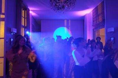 Mur en briques éclairé par des lumières rouges et vertes avec des enceintes noires sur pieds alignées.