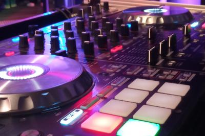 Mur en briques éclairé par des lumières rouges et vertes avec des enceintes noires sur pieds alignées.