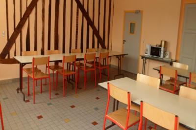 Village rural avec église au centre, maisons environnantes, arbres dénudés et paysage vallonné en arrière-plan.