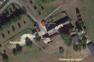 Village rural avec église au centre, maisons environnantes, arbres dénudés et paysage vallonné en arrière-plan.