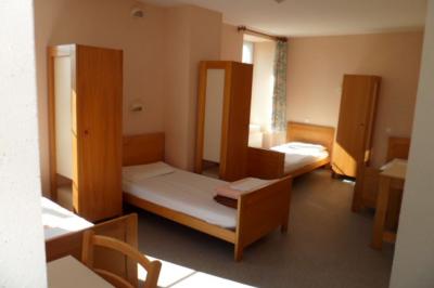 Village rural avec église au centre, maisons environnantes, arbres dénudés et paysage vallonné en arrière-plan.