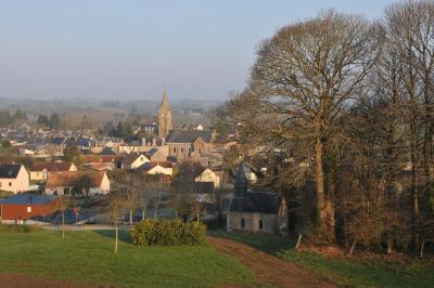 Village rural avec église au centre, maisons environnantes, arbres dénudés et paysage vallonné en arrière-plan.
