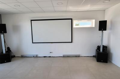 Parking extérieur avec marquages au sol, quelques voitures stationnées, bâtiments et champs en arrière-plan.