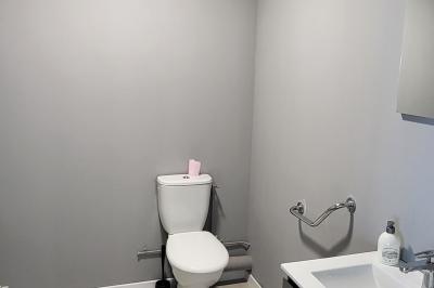 Parking extérieur avec marquages au sol, quelques voitures stationnées, bâtiments et champs en arrière-plan.