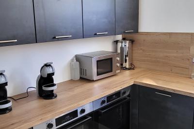 Parking extérieur avec marquages au sol, quelques voitures stationnées, bâtiments et champs en arrière-plan.