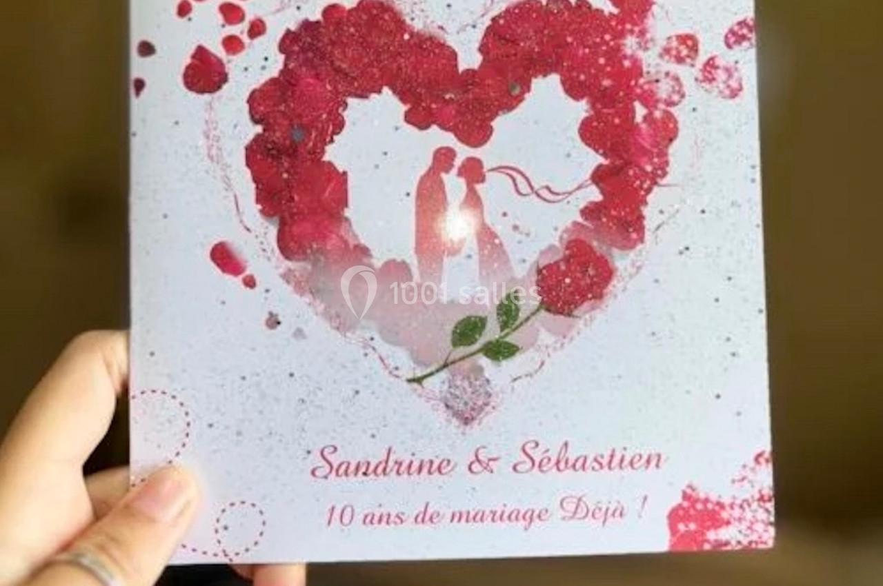 Carte blanche avec un cœur rouge formé de pétales, deux silhouettes au centre et texte célébrant 10 ans de mariage.