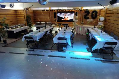 Salle vide avec parquet, murs en bois, décorations dorées et une boule disco suspendue au plafond.