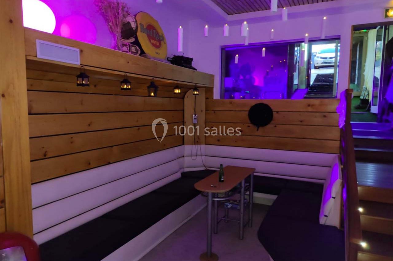 Banquette d'angle en bois et cuir dans un espace éclairé par des lumières violettes, avec une table basse au centre.