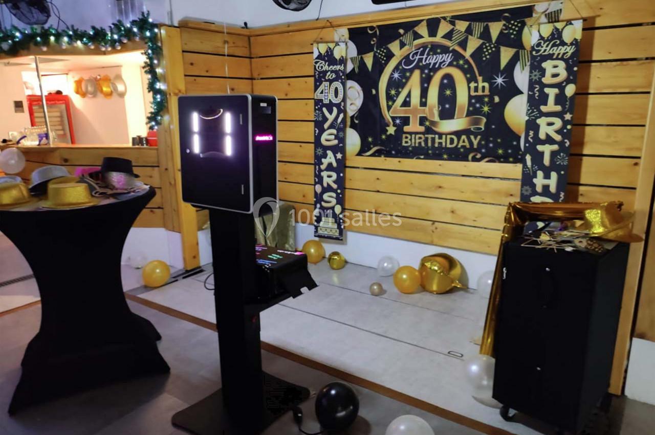 Photobooth installé dans une salle décorée pour un 40e anniversaire, avec ballons et accessoires festifs.