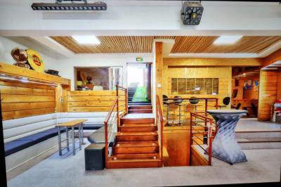 Salle vide avec parquet, murs en bois, décorations dorées et une boule disco suspendue au plafond.