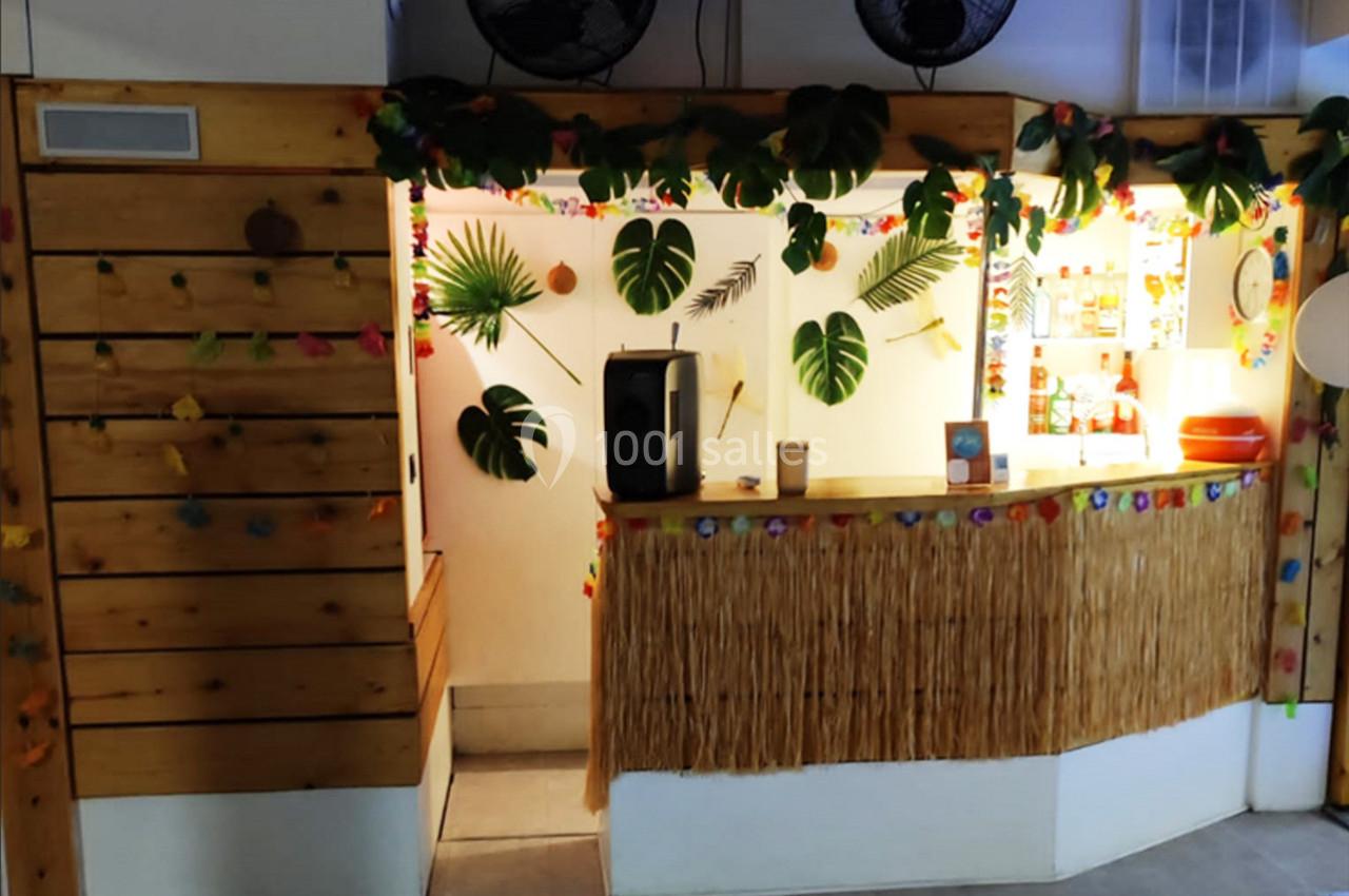 Comptoir décoré de feuilles tropicales, guirlandes colorées et éléments en bois dans une ambiance exotique.