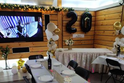 Salle vide avec parquet, murs en bois, décorations dorées et une boule disco suspendue au plafond.