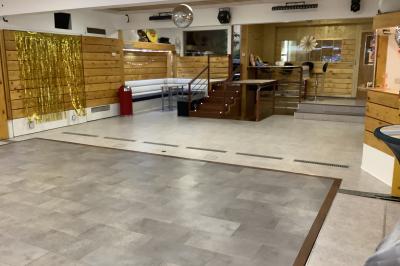 Salle vide avec parquet, murs en bois, décorations dorées et une boule disco suspendue au plafond.