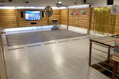 Salle vide avec parquet, murs en bois, décorations dorées et une boule disco suspendue au plafond.