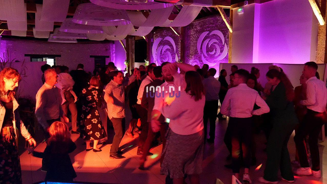 Groupe de personnes dansant dans une salle éclairée par des lumières colorées, ambiance festive.
