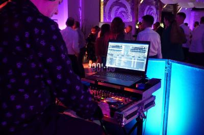 Salle de réception en pierre avec invités assis et debout, décorations florales suspendues et ambiance chaleureuse.