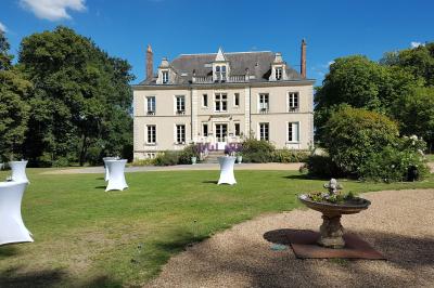 Salle de réception en pierre avec invités assis et debout, décorations florales suspendues et ambiance chaleureuse.