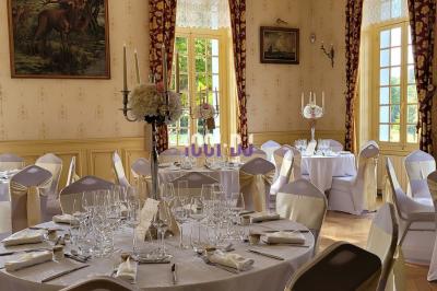Salle de réception en pierre avec invités assis et debout, décorations florales suspendues et ambiance chaleureuse.