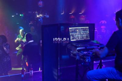 Salle de réception en pierre avec invités assis et debout, décorations florales suspendues et ambiance chaleureuse.