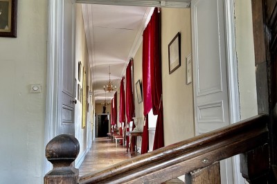 Château éclairé de nuit avec des lumières colorées, entouré de buissons et de tentes blanches sous un ciel nuageux.