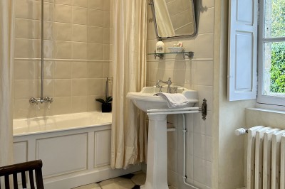 Château éclairé de nuit avec des lumières colorées, entouré de buissons et de tentes blanches sous un ciel nuageux.