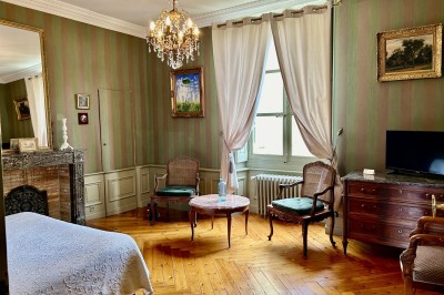 Château éclairé de nuit avec des lumières colorées, entouré de buissons et de tentes blanches sous un ciel nuageux.