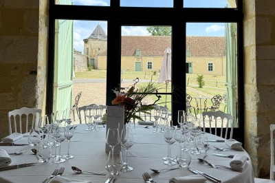 Château éclairé de nuit avec des lumières colorées, entouré de buissons et de tentes blanches sous un ciel nuageux.