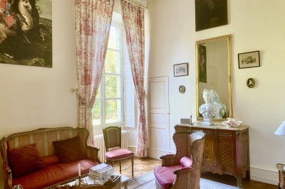 Château éclairé de nuit avec des lumières colorées, entouré de buissons et de tentes blanches sous un ciel nuageux.