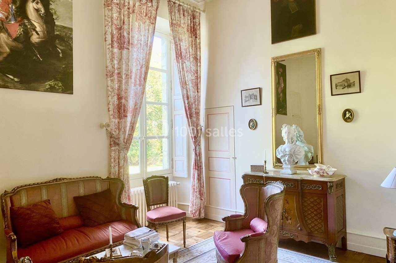 Salon élégant avec mobilier ancien, rideaux en toile de Jouy, tableaux et buste décoratif sur une commode en bois.