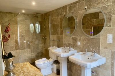 Château éclairé de nuit avec des lumières colorées, entouré de buissons et de tentes blanches sous un ciel nuageux.