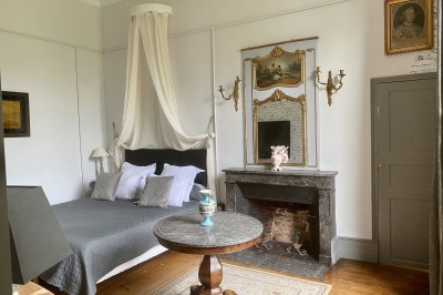 Château éclairé de nuit avec des lumières colorées, entouré de buissons et de tentes blanches sous un ciel nuageux.