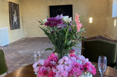Château éclairé de nuit avec des lumières colorées, entouré de buissons et de tentes blanches sous un ciel nuageux.
