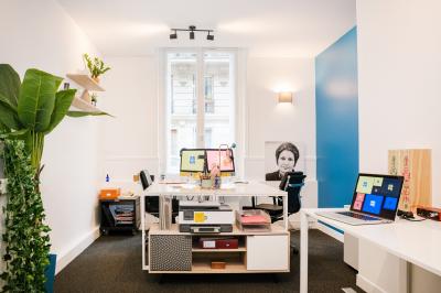 Trois personnes assises et debout dans un intérieur moderne avec des panneaux muraux décoratifs en arrière-plan.