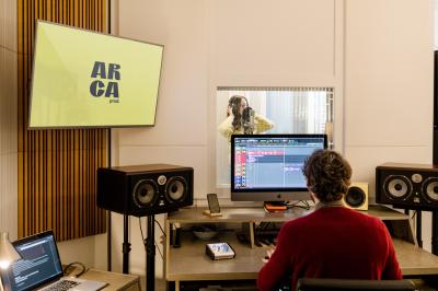 Trois personnes assises et debout dans un intérieur moderne avec des panneaux muraux décoratifs en arrière-plan.